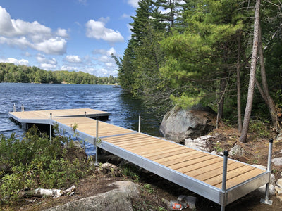 Quai flottant usagé en bois menant à une rive boisée au Québec